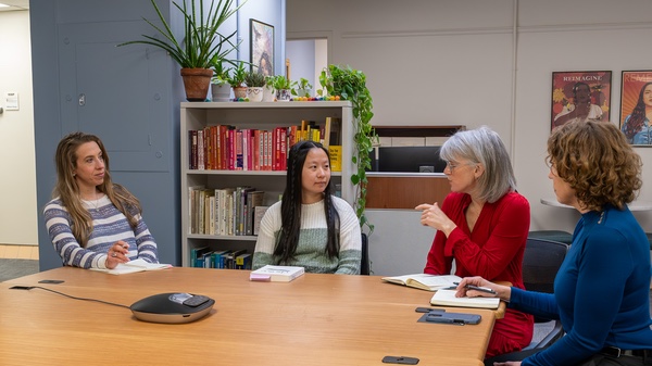 CORE colleagues meet and discuss around a table in a room with houseplants and colorful books on a bookcase. Photo by Rob Garza / UW Department of Ob-Gyn